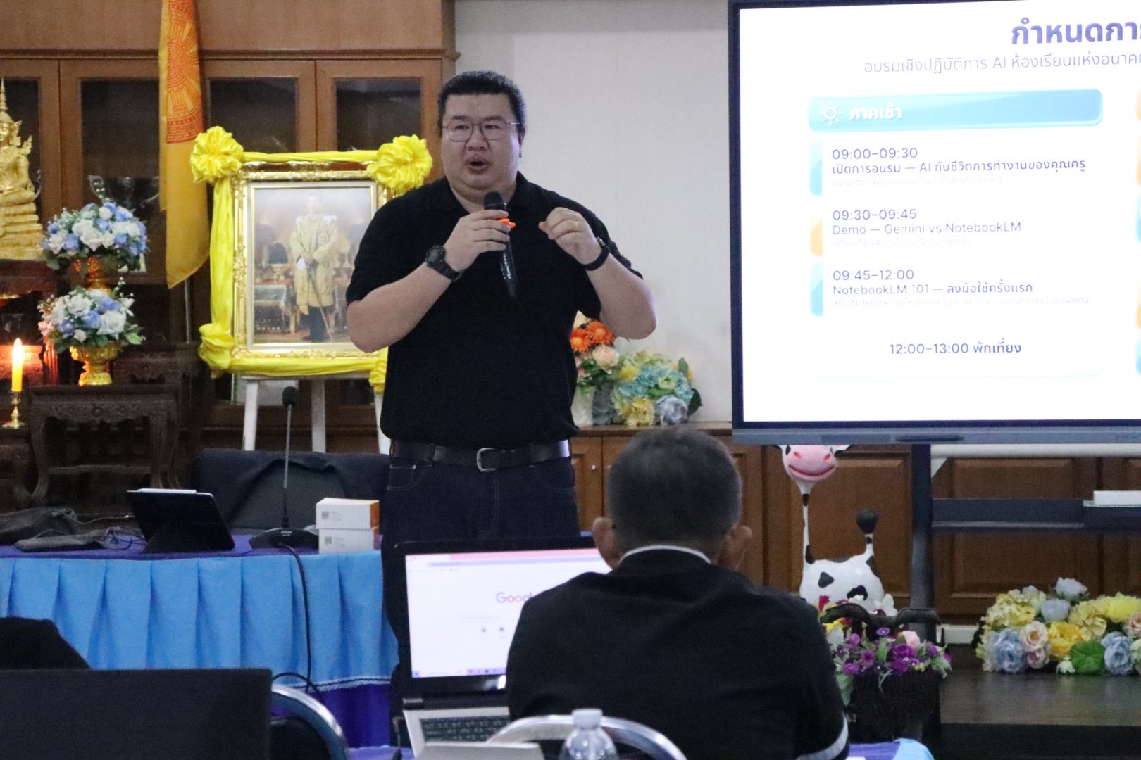 วิทยากรกำลังพูดหน้าจอแสดงกำหนดการอบรมในห้องประชุม